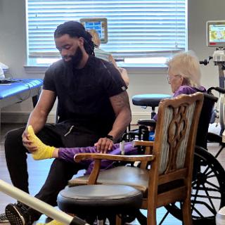 A caregiver assisting a young patient with physical therapy in a rehabilitation setting.