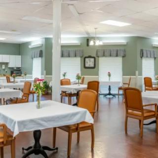 An empty dining area with neatly arranged tables and chairs, decorated with small flower vases.