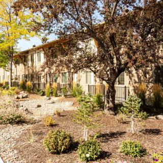 A residential apartment building surrounded by landscaped gardens on a sunny day.