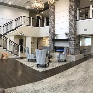 A modern and spacious lobby with a central fireplace, stylish seating area, and elegant chandeliers.