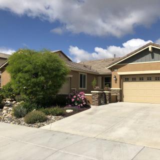 A suburban house with a well-maintained garden and a two-car garage under a partly cloudy sky.