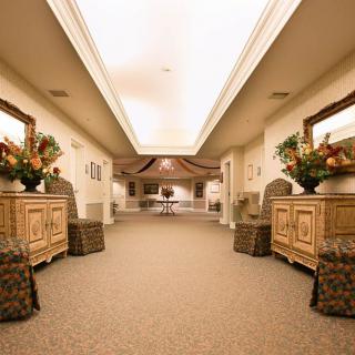 A well-lit hallway with elegant furniture and decorative flower arrangements.