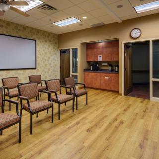 A quiet office waiting room with rows of chairs and a TV screen.