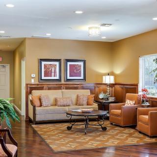 A cozy living room with warm colors, featuring a sofa, armchairs, and decorative artwork.