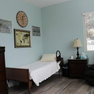 A simple bedroom with a single bed, wall clock, and various decorations.