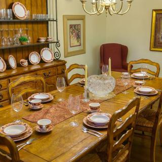 A cozy dining room with a wooden table set for a meal, surrounded by chairs and adorned with a chandelier.