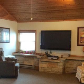Cozy living room with a wood ceiling and large television.