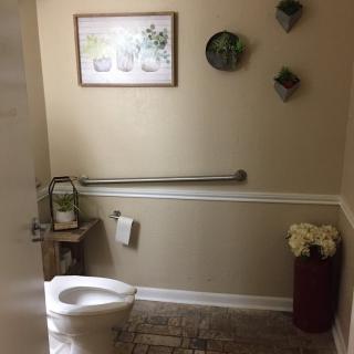 A neatly decorated bathroom with wall art and plants.