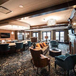 A cozy and modern lounge area featuring comfortable seating, a stylish bar, and warm lighting.