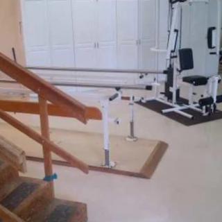 A room equipped with rehabilitation and physical therapy equipment, including parallel bars and exercise machines.