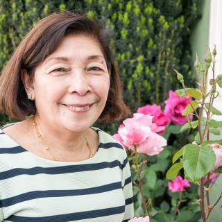 A woman smiling in a garden with flowers.
