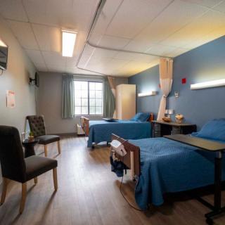 A hospital room with two beds and basic amenities.