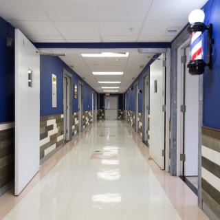 A brightly lit hallway with a row of doors and a barber pole on the wall.