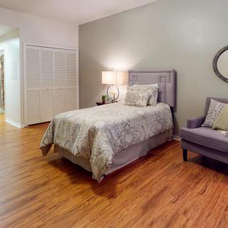 A cozy bedroom with a single bed, wooden flooring, and an armchair.