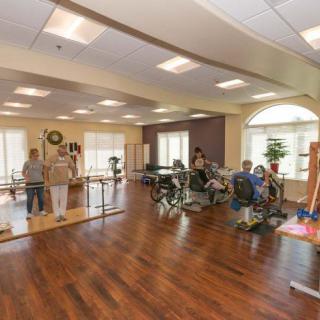 A rehabilitation center with various exercise equipment and patients engaging in physical therapy activities.
