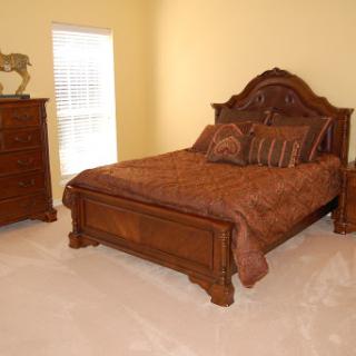 A cozy bedroom featuring a wooden bed with decorative pillows and matching nightstand.
