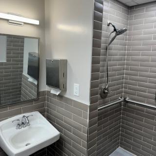 A modern bathroom featuring a shower, sink, and mirror with elegant tile work.
