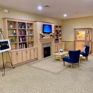 A cozy library seating area with bookshelves, a fireplace, and comfortable chairs.
