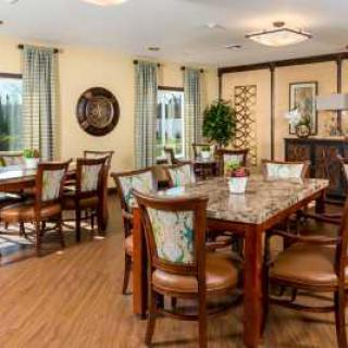 A cozy dining room with multiple tables and chairs, decorated with elegant curtains and lighting.