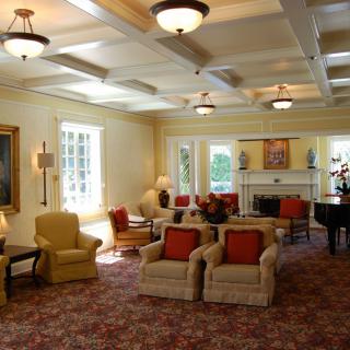 A cozy living room with comfortable armchairs, a fireplace, and a grand piano.
