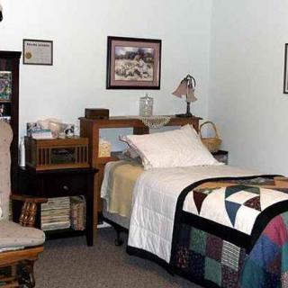 A cozy vintage-style bedroom with a quilt-covered bed and wooden furniture.