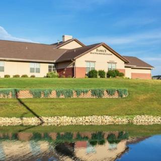 A house by a lake with reflections in the water and a clear blue sky.