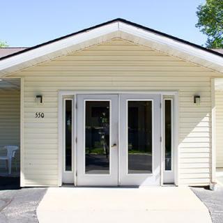 A residential building entrance with double glass doors and yellow siding.