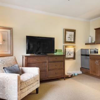 A cozy living room area with a television, armchair, and kitchenette.