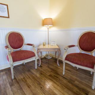 A cozy corner featuring two elegant chairs and a warm lamp, creating a welcoming atmosphere.