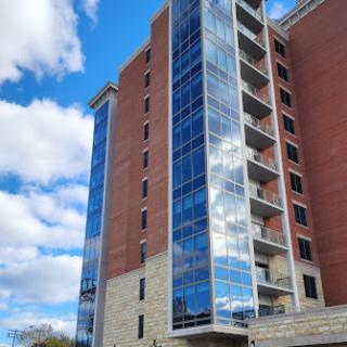 A striking modern building featuring a sleek glass facade against a clear blue sky.