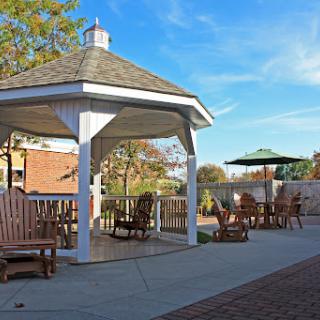 A serene outdoor gazebo surrounded by comfortable seating, perfect for relaxation on a sunny day.