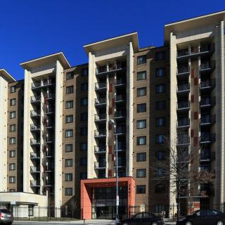 A modern multi-story apartment building under a clear blue sky.