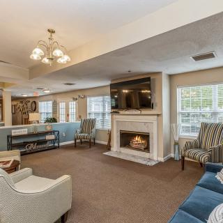 A cozy living room with a fireplace, multiple seating options, and a television mounted above the mantel.