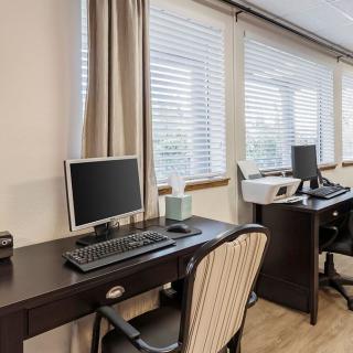 A clean office workspace with computers and desks near large windows.