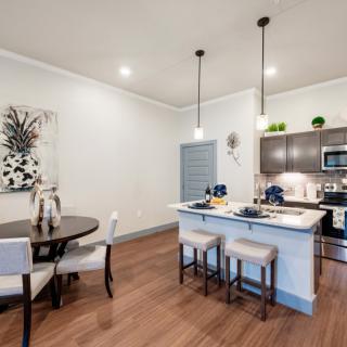 A modern open-concept kitchen and dining area featuring an island counter and pendant lighting.