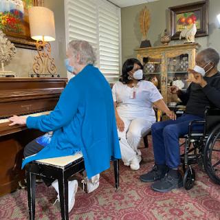 A group of elderly individuals enjoying a musical moment together, with one person playing the piano.
