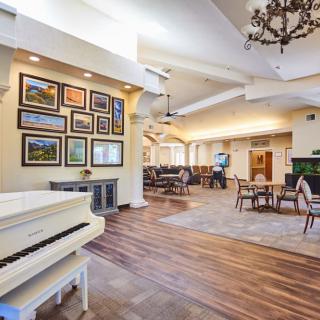 A spacious living room with a grand piano, artwork on the walls, and a cozy seating area.