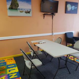 A small classroom setting with a table, chairs, and colorful play mat.