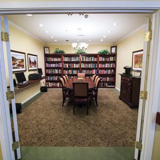 A well-organized library room set up for meetings, featuring bookshelves and a central conference table surrounded by chairs.