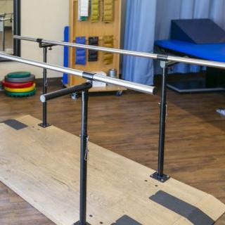 A physical therapy room featuring parallel bars used for rehabilitation exercises.