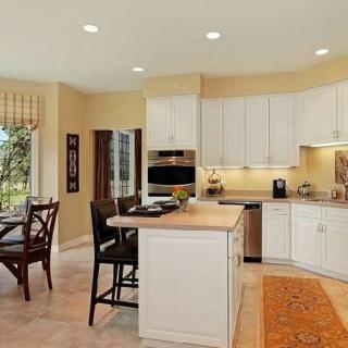 A bright kitchen with white cabinets and an island, featuring a dining area by the window.