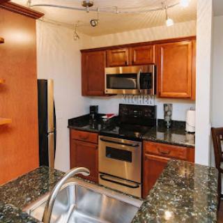 A modern kitchen featuring wooden cabinets, stainless steel appliances, and a granite countertop.