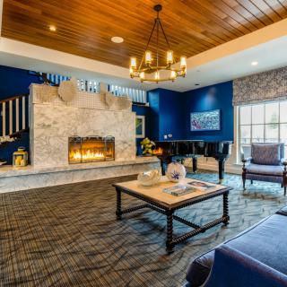 A luxurious living room with a modern fireplace and a chandelier, featuring blue walls and a wooden ceiling.