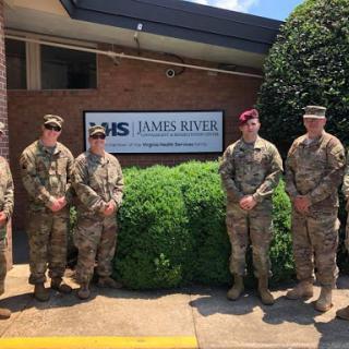 A group of soldiers stands proudly in front of a facility.