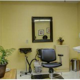 A cozy hair salon setup with a chair, mirror, and sink.