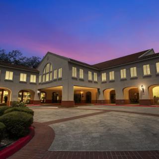 A well-lit building with a courtyard captured at dusk.