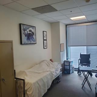 A quiet hospital room featuring a bed, a wheelchair, and artwork on the wall.