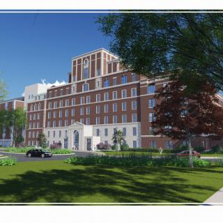 A large hospital building with a classic architectural design, surrounded by trees and greenery on a sunny day.