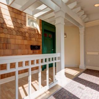 A sunlit porch featuring a green door and wooden paneling.
