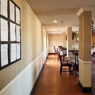 A restaurant interior with a hallway leading to a dining area, featuring tables and chairs.